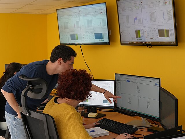 Two JUWI employees look at data on monitors in the control room