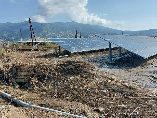 Solar power plant covered in debris after flooding. Montains in the background.